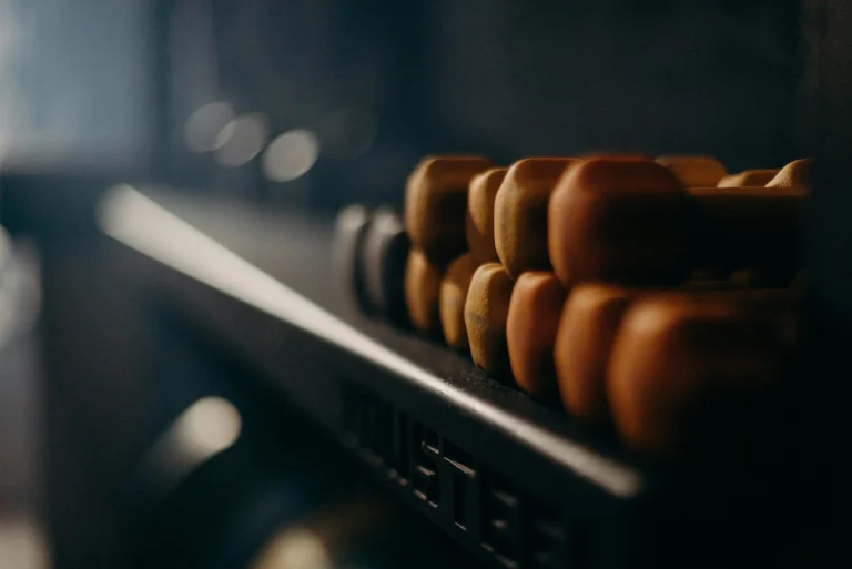 Close-up of orange dumbbells stacked on a gym rack in soft lighting
