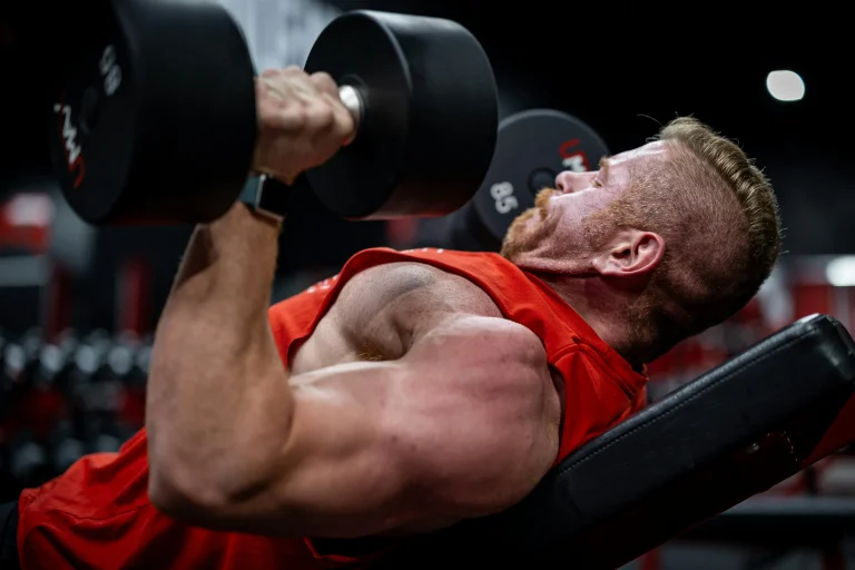 Person performing an incline dumbbell press with 85 lb weights in a focused gym environment.