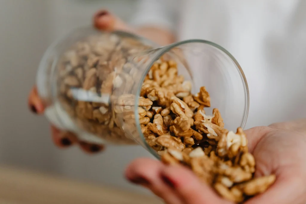 Close-up of walnuts being poured from a glass into a hand, showing a healthy snack option.