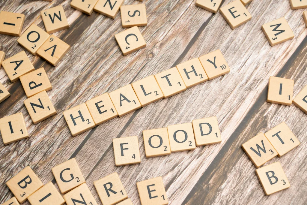 The words Healthy Food spelled out using scrabble-style wooden tiles on a rustic wooden background
