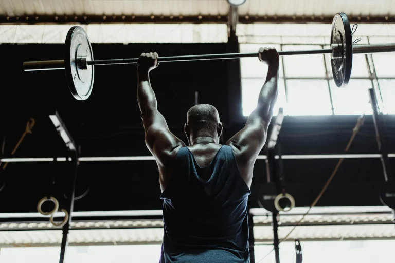 Athlete lifting barbell overhead during workout in gym