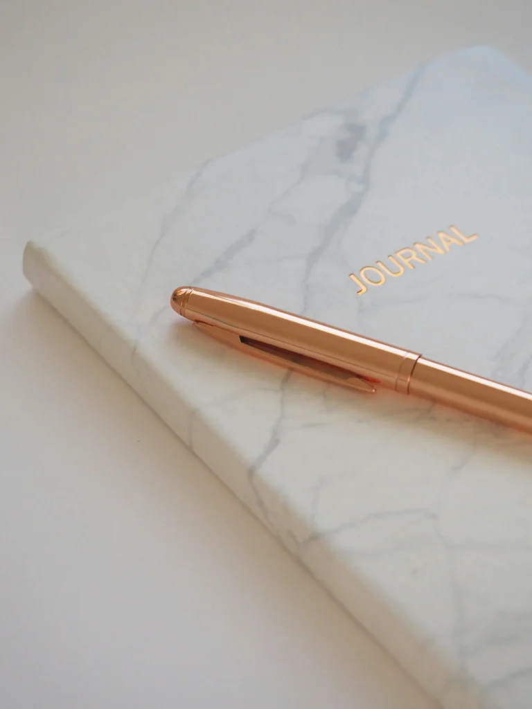 Marble journal with a gold pen placed on top, symbolizing reflection, writing, and personal growth