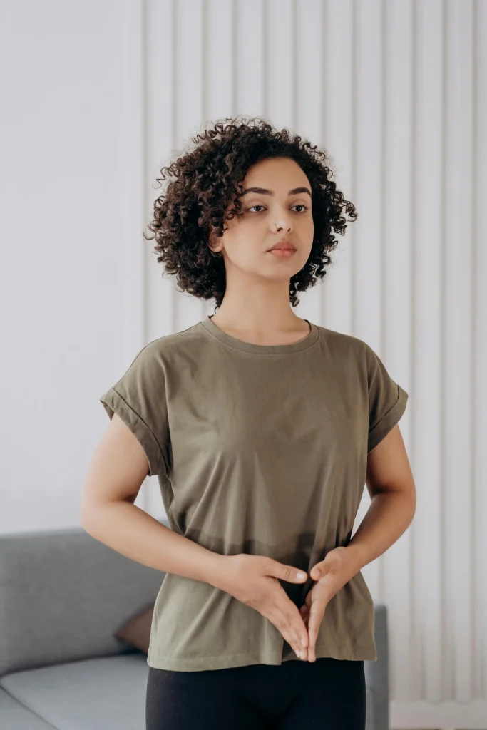Woman practicing mindful breathing with hands in a meditative position indoors