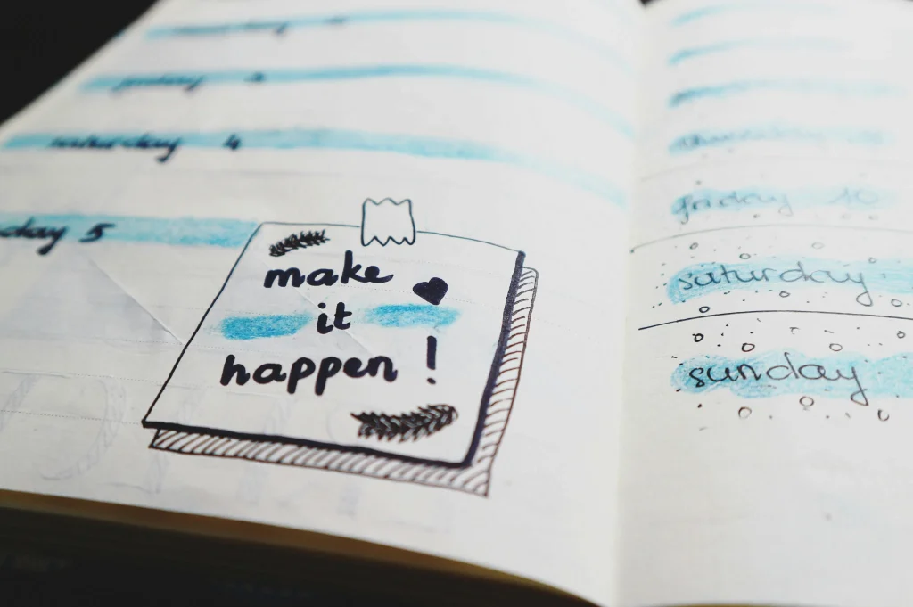 Open journal with handwritten quote make it happen and weekly planner