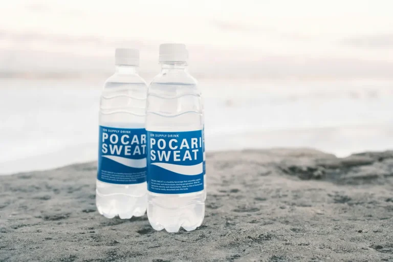 Two Pocari Sweat bottles placed on sandy beach, emphasizing hydration and electrolyte balance.