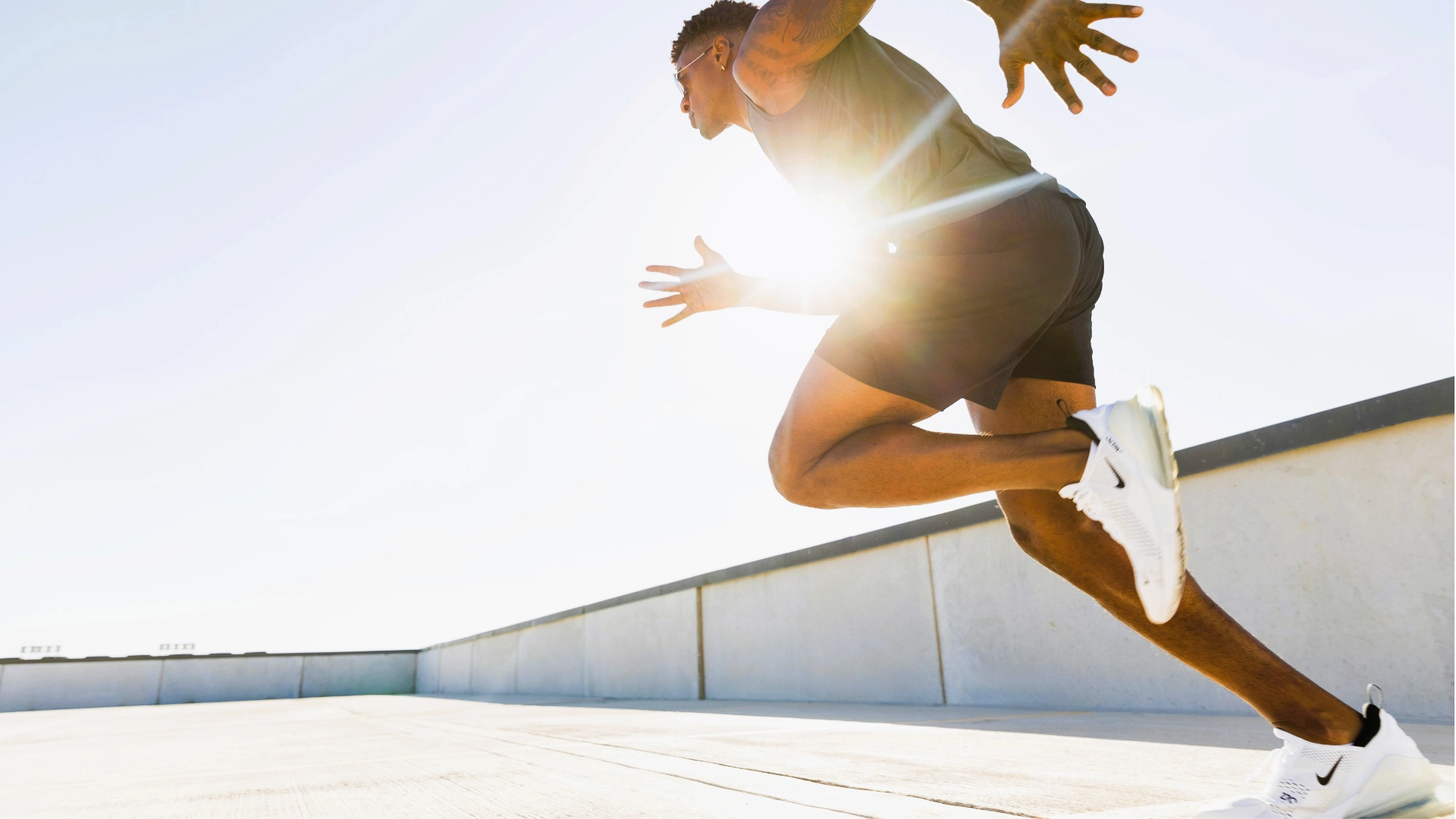 Athlete sprinting outdoors in the sunlight, wearing sportswear and running shoes