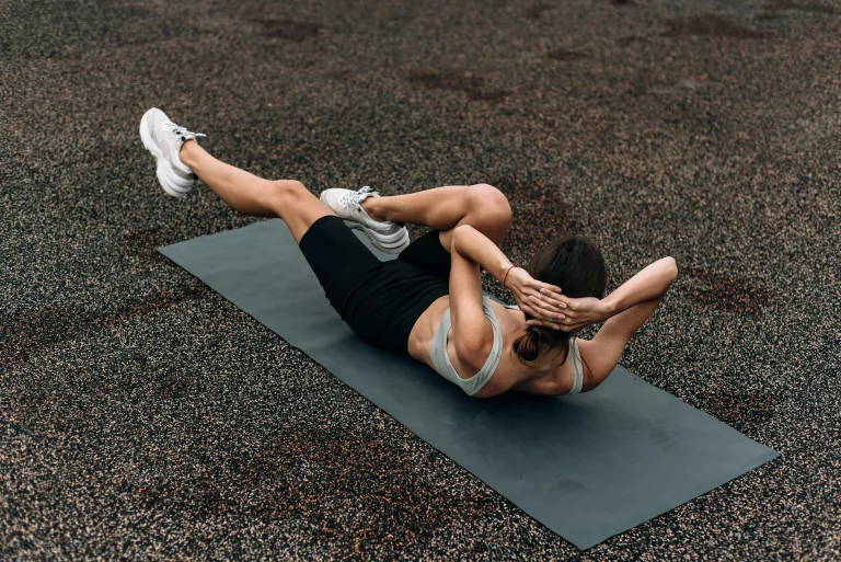 Woman performing bicycle crunch workout on exercise mat outdoors
