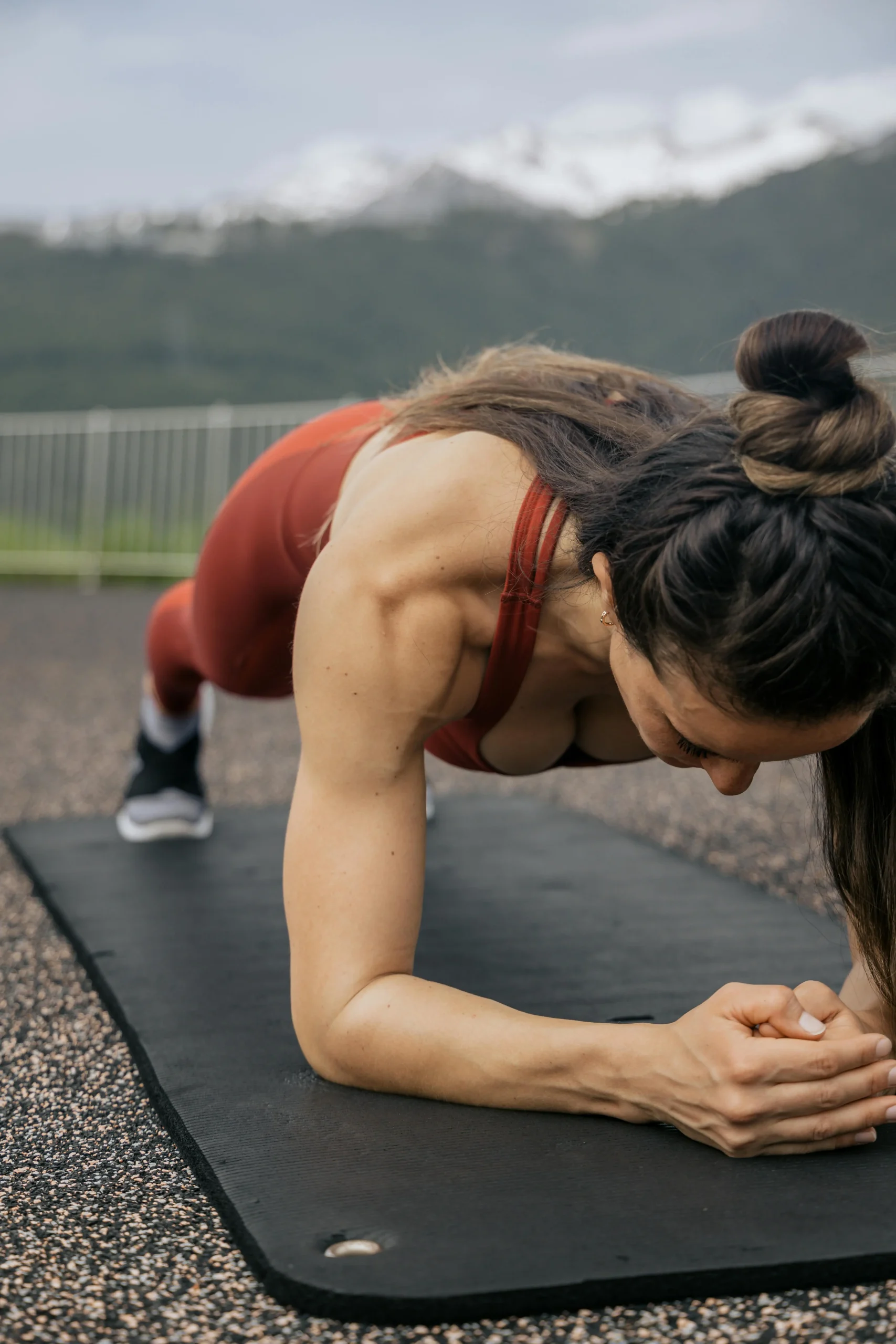 Fit woman holding plank position on exercise mat outdoors