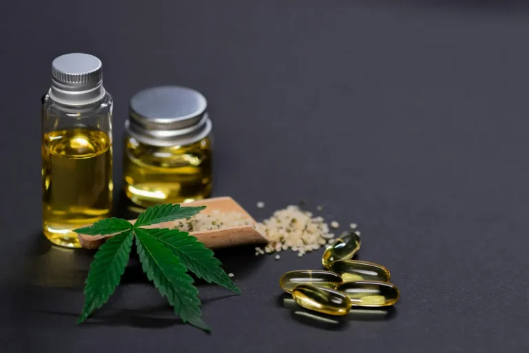 Hemp oil bottles, capsules, seeds, and a hemp leaf arranged on a dark surface symbolizing natural wellness and supplements.