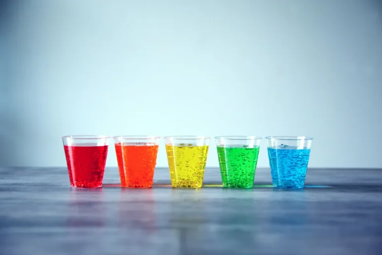 Five colorful glasses of sparkling drinks in red, orange, yellow, green, and blue symbolizing healthy hydration choices.